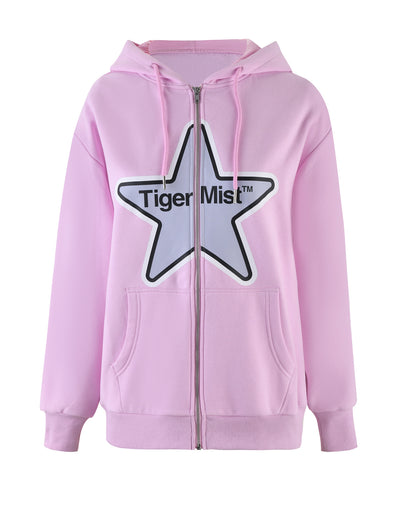 The LUMEN ZIP FRONT HOODIE - PINK by TIGERMIST is a light pink loungewear hoodie with an oversized silhouette. It features a large front pocket, drawstrings on the hood, and is made from fleece-lined tracksuiting fabric. The front prominently displays a white star with a black outline and the text "Tiger Mist" written inside the star.