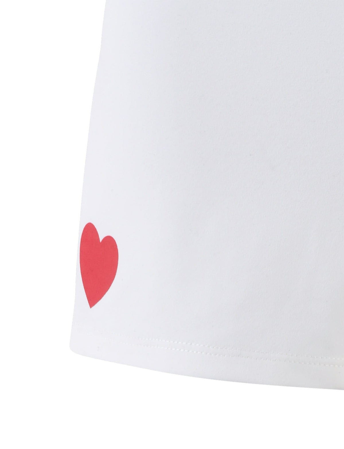 Close-up of the TIGERMIST DELANEY SHORT - WHITE fabric featuring a small, solid red heart design near the hem on the left side. The simple heart adds a touch of whimsy to the otherwise plain material.