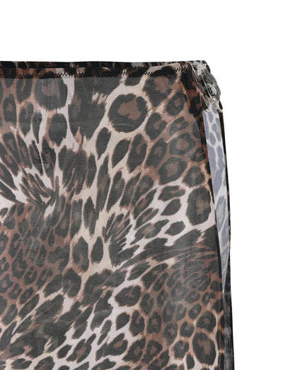 Close-up of the Cynthia Mini Mesh Skirt from TIGERMIST, featuring a leopard print pattern in shades of brown, black, and white. The fabric drapes at the top right edge and is stitched with a visible hem, suggesting this chic piece might easily complement any wardrobe.