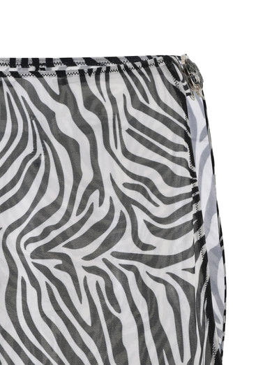 Close-up of the CYNTHIA MINI MESH SKIRT - BLACK : ZEBRA fabric by TIGERMIST, showcasing a black and white zebra print pattern. The skirt features stripes that mimic a zebra's coat, with visible black stitching along the edge and a partially visible metal zipper on the right side.