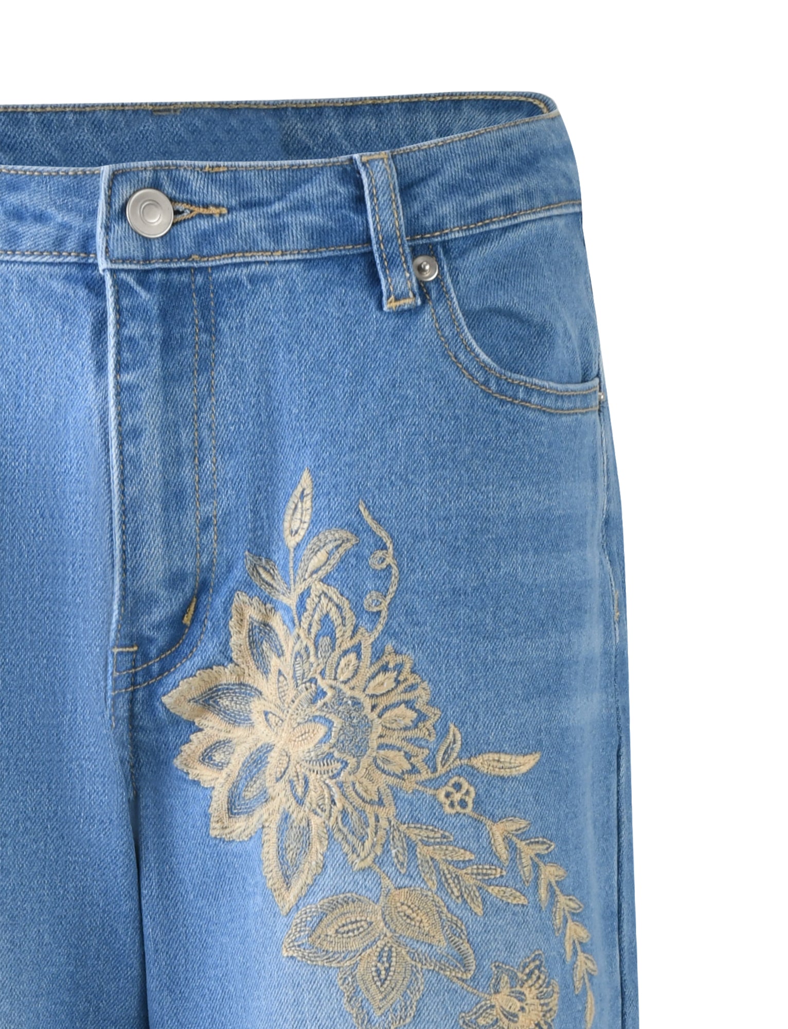 Close-up of a pair of VEGA JEANS in mid blue denim from TIGERMIST, featuring an intricate gold floral embroidery pattern on the upper left thigh area. The jeans have a button and zipper closure, along with standard belt loops and pockets.