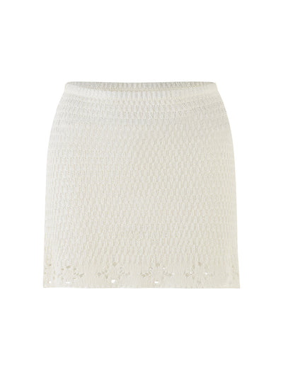 The JANAI SKIRT - WHITE : CREAM by TIGERMIST is displayed against a plain background. This mini length skirt features a subtle textured pattern and a slightly flared hem with delicate crochet detailing. It has a fitted waistband for a snug fit.