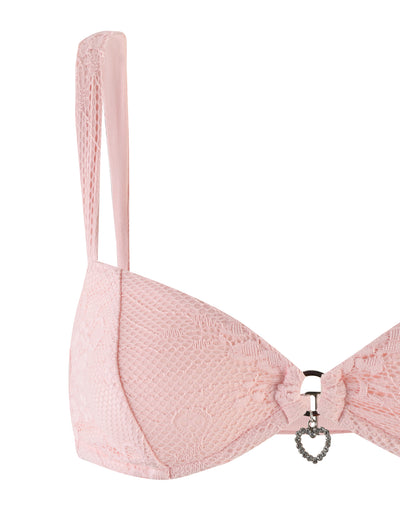 A pastel pink Xadie Top by Tigermist, featuring thin straps and a small heart-shaped charm at the center. The intricate lace pattern adds a delicate and feminine touch to the design.