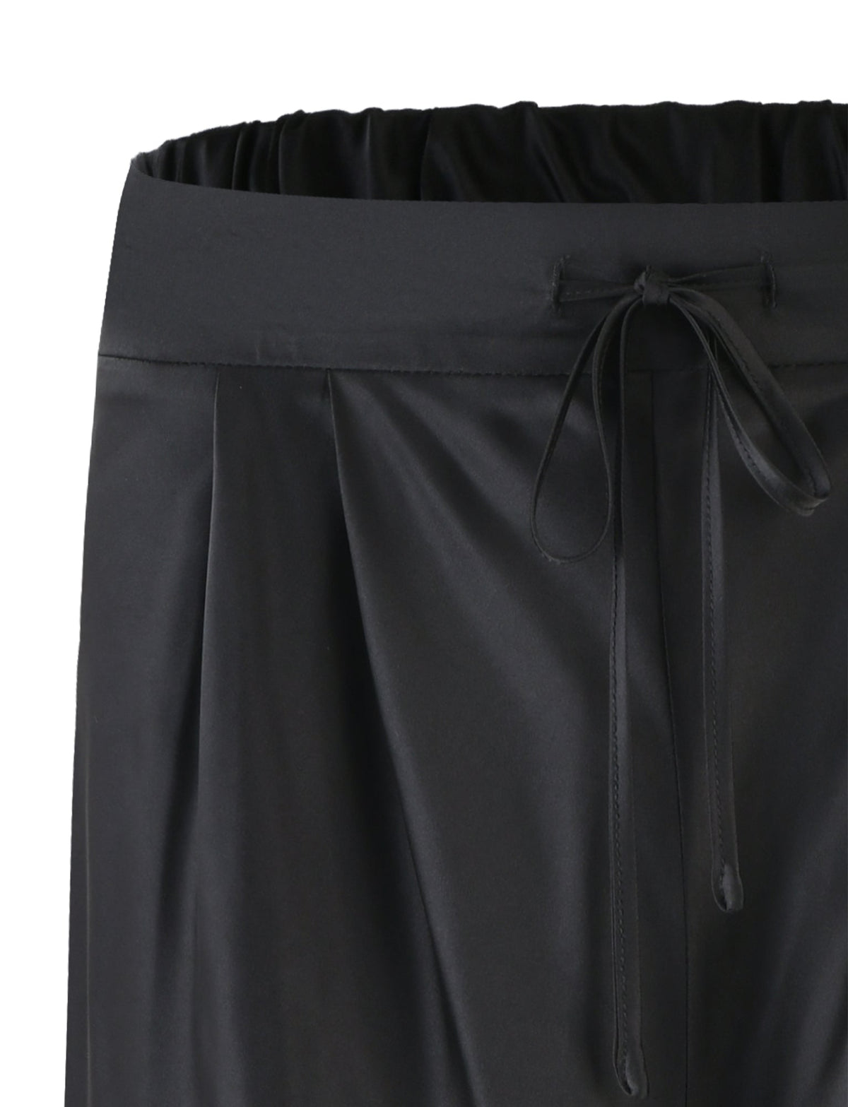 Close-up of the TIGERMIST ALINA PANT - BLACK featuring an elastic waistband and a drawstring bow at the front. The pants are made of a smooth, slightly shiny fabric with a subtle pleated design below the waistband.