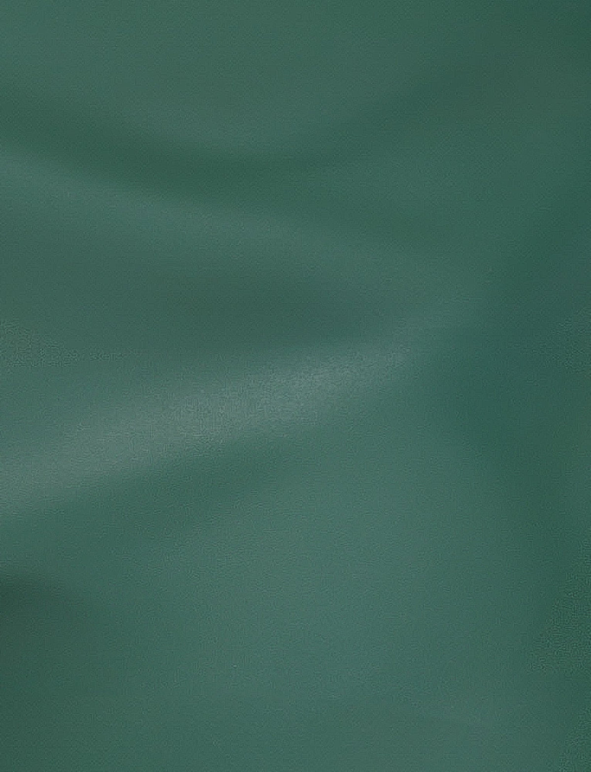 The surface of the MCKAY TOP - GREEN by TIGERMIST is smooth and features a deep green color. The texture resembles silk, with soft, flowing creases and a matte finish. Under the right lighting, the gentle curves are highlighted, adding depth and a subtle shimmer to the material, consistent with Tiger Mist's luxurious fabric designs.