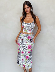 A woman with long hair is wearing a TIGERMIST's IRIE SKIRT - MULTI : ZEBRA, a sleeveless, form-fitting dress adorned with a mix of zebra prints and pink floral patterns. The dress features side cutouts at the waist. She stands against a plain, light-colored background and looks directly at the camera.