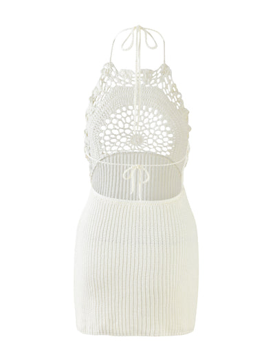 The MACELINE DRESS - WHITE from TIGERMIST is a sleeveless, backless crochet dress with an intricate floral-patterned design on the upper back and neck area. It features adjustable tie straps at the neck and middle back, complemented by a ribbed, knee-length skirt.