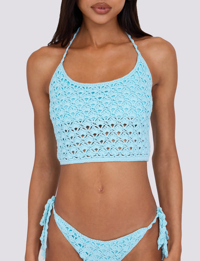 A person is wearing the light blue SUNNIVA BIKINI TOP from TIGERMIST, featuring a high-necked crop top and matching tie-side bottoms. The background is a plain light gray.