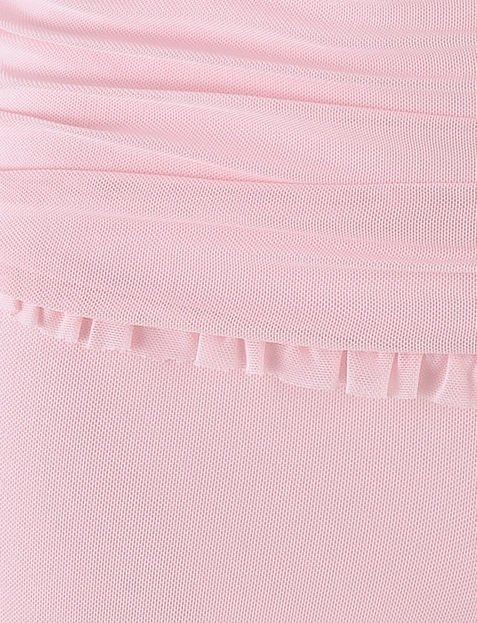 Close-up of the GINNY SHORT - PINK in baby pink from TIGERMIST. This finely textured fabric features ruched details at the top and a thin strip of ruffled trim running horizontally near the center. The high-stretch material, combined with its texture and design elements, gives it a delicate and decorative appearance.