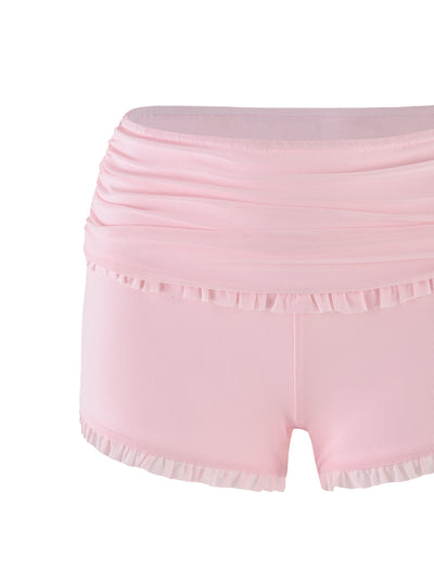 The GINNY SHORT - PINK : BABY PINK by TIGERMIST is a pair of baby pink ballet shorts with a ruched waistband and ruffled trim at both the waistline and leg openings, providing a delicate, feminine look. The high-stretch fabric ensures comfort and flexibility, making it perfect for dance or athletic activities.