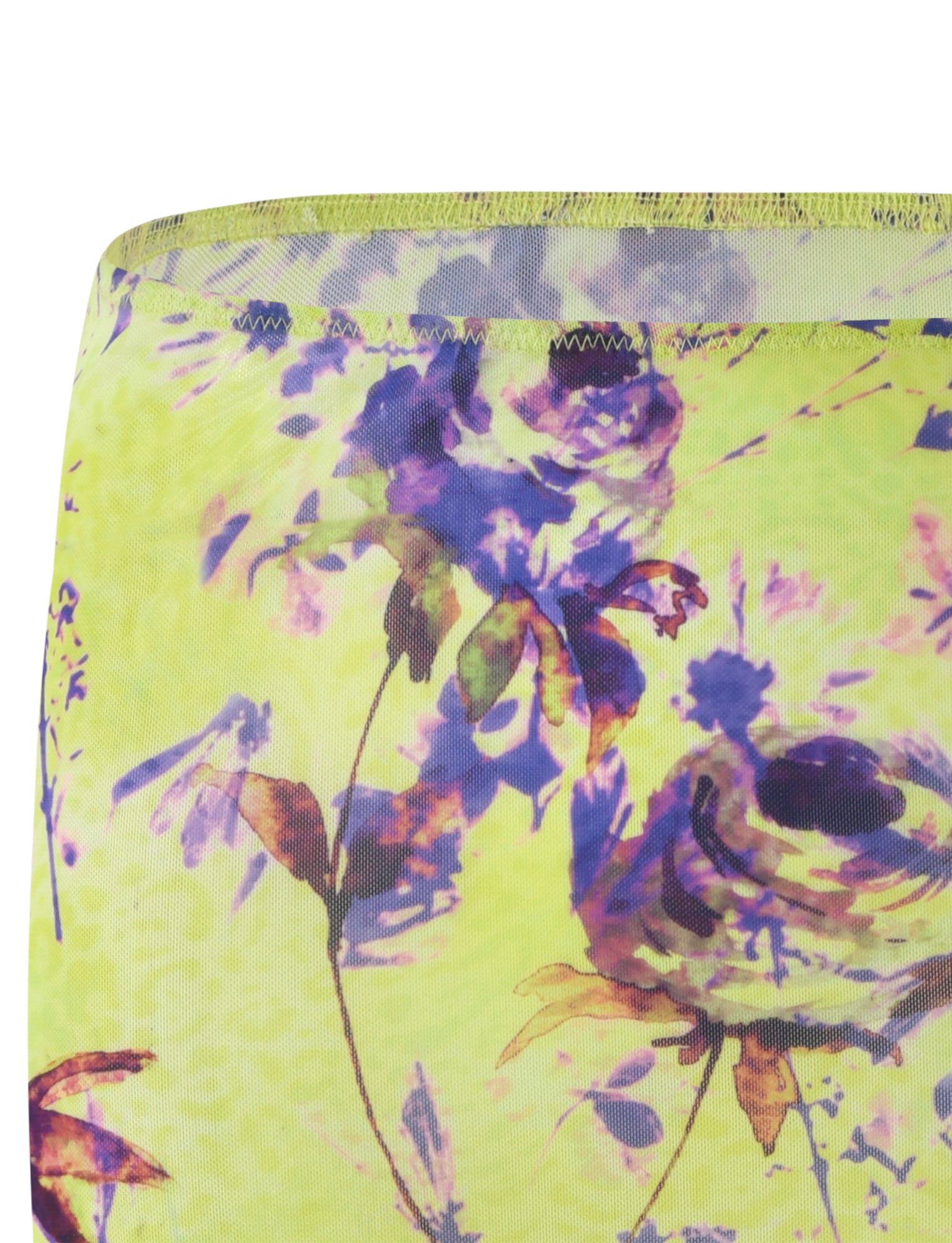 A close-up of the KELLAN SKIRT - GREEN from TIGERMIST, featuring an abstract floral design by Poppy Floral. The background is green, adorned with flowers in shades of purple and light pink. The stitching on the top edge is visible, and the fabric appears to be translucent with a soft, lightweight texture.