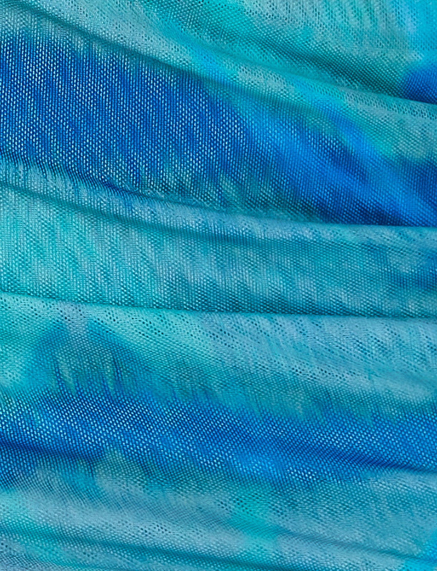 An abstract image featuring layers of vibrant blue and teal fabric with various textures and patterns, reminiscent of the dynamic design of the TINSLEY SKORT - MULTI : ABSTRACT TIE DYE by TIGERMIST. The overlapping and slightly transparent material creates a dynamic interplay of light and shade, evoking a sense of fluidity and movement.