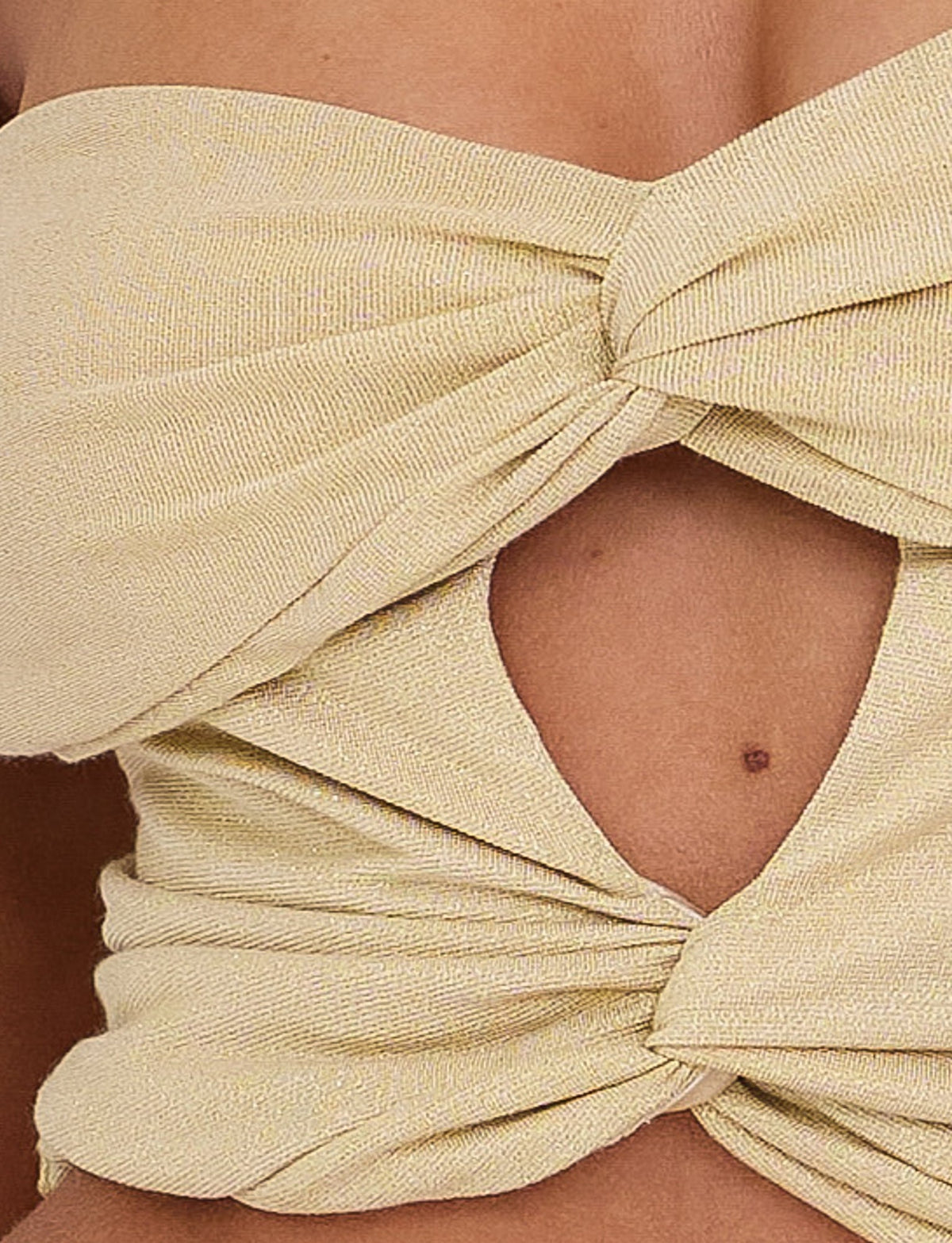 Close-up of the LYNSEY TOP - GOLD from TIGERMIST, featuring light yellow textured fabric with knotted detailing. The fabric forms a twist at the front, creating a small triangular cutout, and is shown worn by a person with a bit of skin and a small mole visible near the cutout.