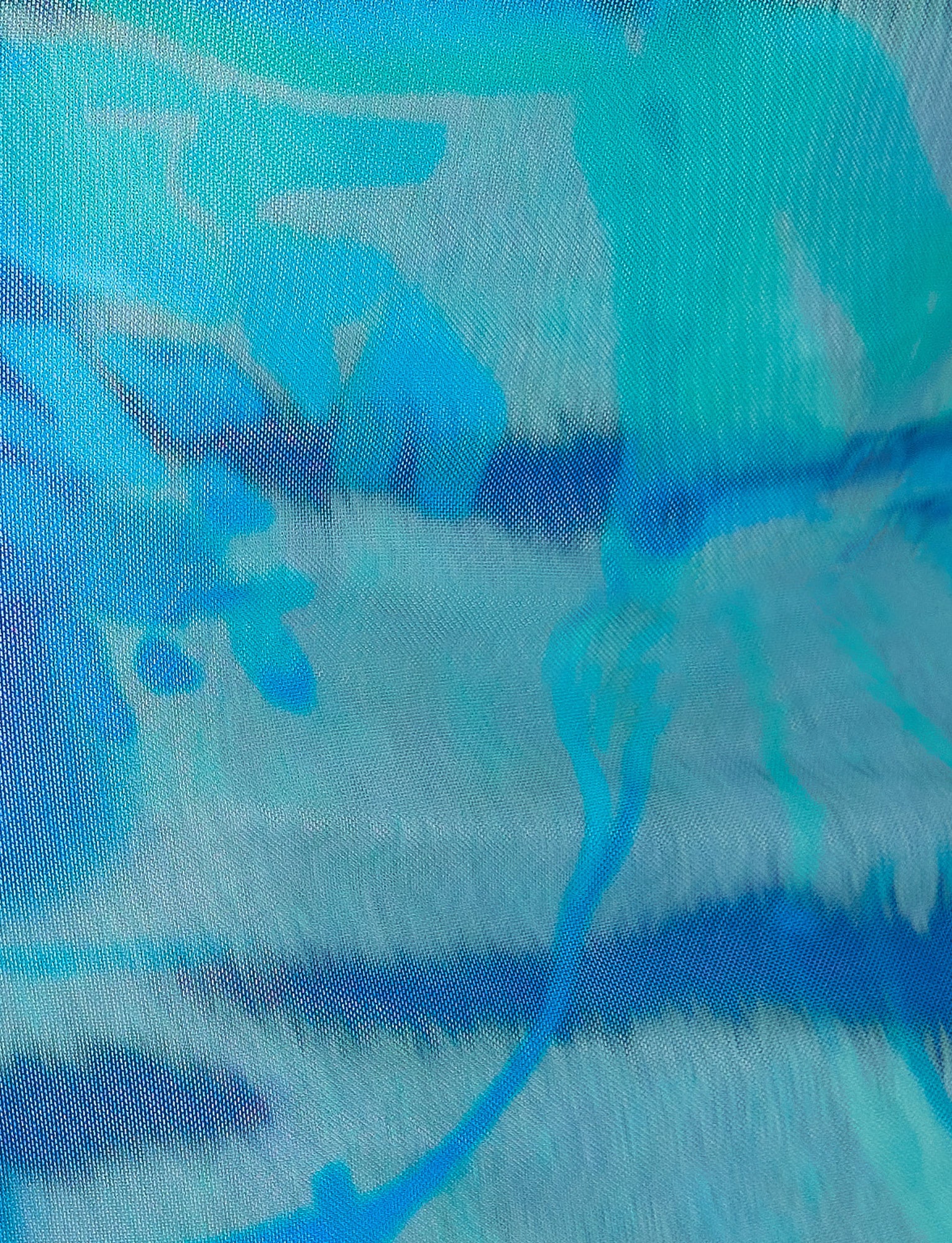 A close-up view of the TENLEY DRESS - MULTI : ABSTRACT TIE DYE by TIGERMIST showcases its vibrant abstract pattern in shades of blue, teal, and white. The design features brushstroke-like textures and fluid shapes, creating a dynamic and visually engaging composition.