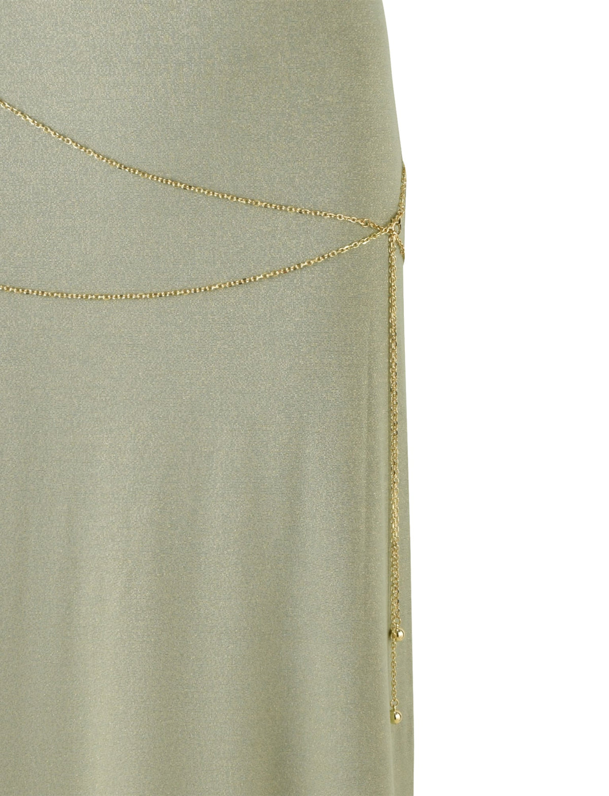 A close-up of TIGERMIST's OPELI MAXI DRESS - GREEN SPARKLE shows a light green, shimmery dress with a thin gold chain belt draped asymmetrically around the waist, secured by a small clasp on the right side. The chain adds an elegant touch and subtle decoration to the simple maxi-length design.