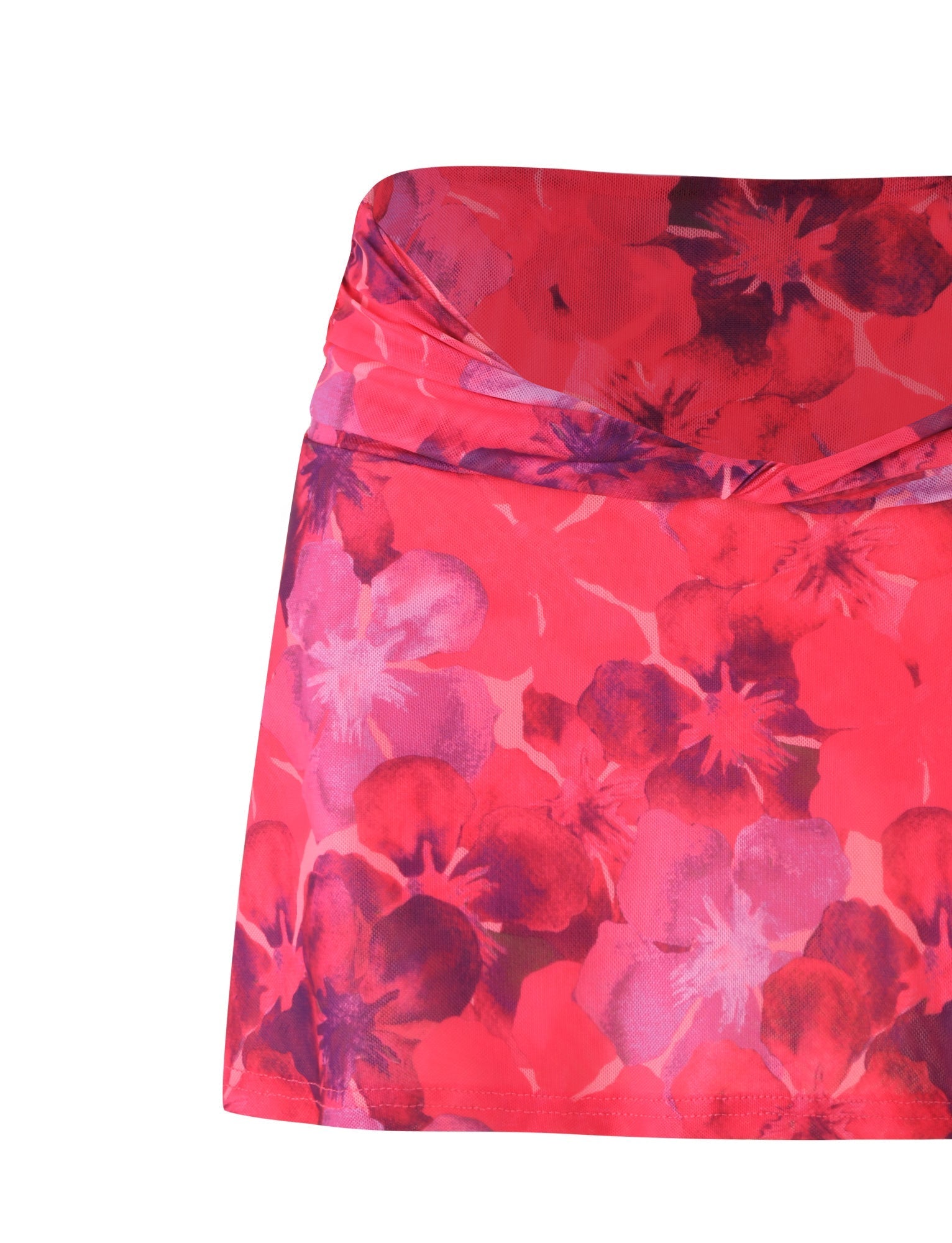 A close-up view of the AMETHYST SKORT - PINK : HIBISCUS by TIGERMIST showcases its vibrant red and pink floral pattern, featuring a twist detail at the waist. The large flowers in various shades create a bold and colorful design, while the light, flowy fabric provides an airy feel perfectly complemented by its elegant mesh fabrication.