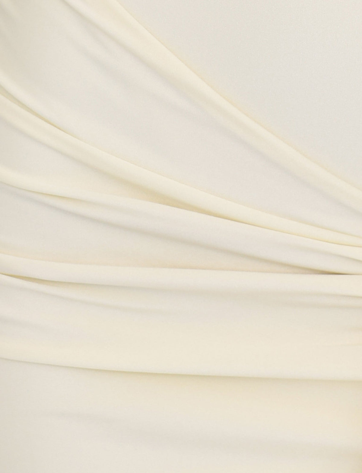 Close-up of soft, butter-yellow fabric from the ELYSIA DRESS by TIGERMIST. The material exhibits gentle, overlapping folds and draping with a smooth, slightly shiny texture, creating an elegant and refined appearance reminiscent of shimmer jersey fabrication.