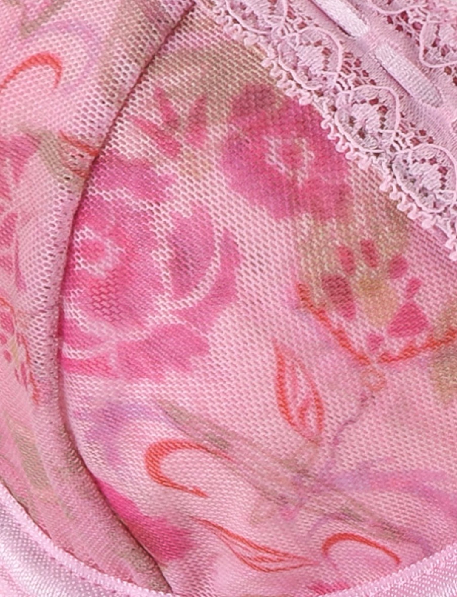 A close-up of the PANDORA MESH SET - PINK : DELICATE FLORAL by TIGERMIST shows a fabric adorned with a pink floral lace pattern in various shades of pink and green. The material features delicate lace trim at the top and adjustable shoulder straps, complementing the design that includes different hues of pink flowers and green leaves on a light pink background.