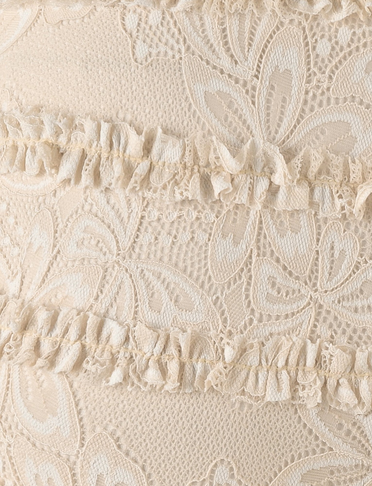 Close-up of the ANELISA SHORT - WHITE : LACE by TIGERMIST, showcasing intricate beige lace and ruffled details. The lace pattern features delicate floral motifs, while horizontal bands of ruffles add texture and dimension to the ornate design, making it perfect for a fashionable mid-rise mini short.