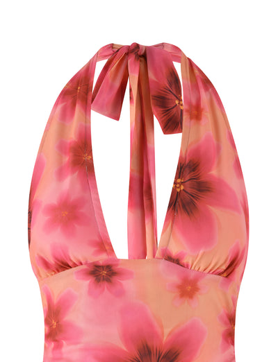 A close-up of the TIGERMIST FRANCIS TOP - MULTI : OMBRE : FLORAL, showcasing a halter neck design with large pink flowers that have darker centers on a peach background. The top features ties at the back of the neck and is made from lightweight mesh fabric, making it perfect for warm weather.