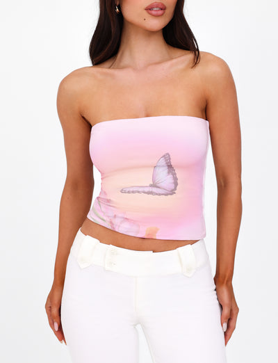 A woman is wearing the AMBROSE BOOB TUBE - PINK from TIGERMIST, paired with white pants. The background is plain white.