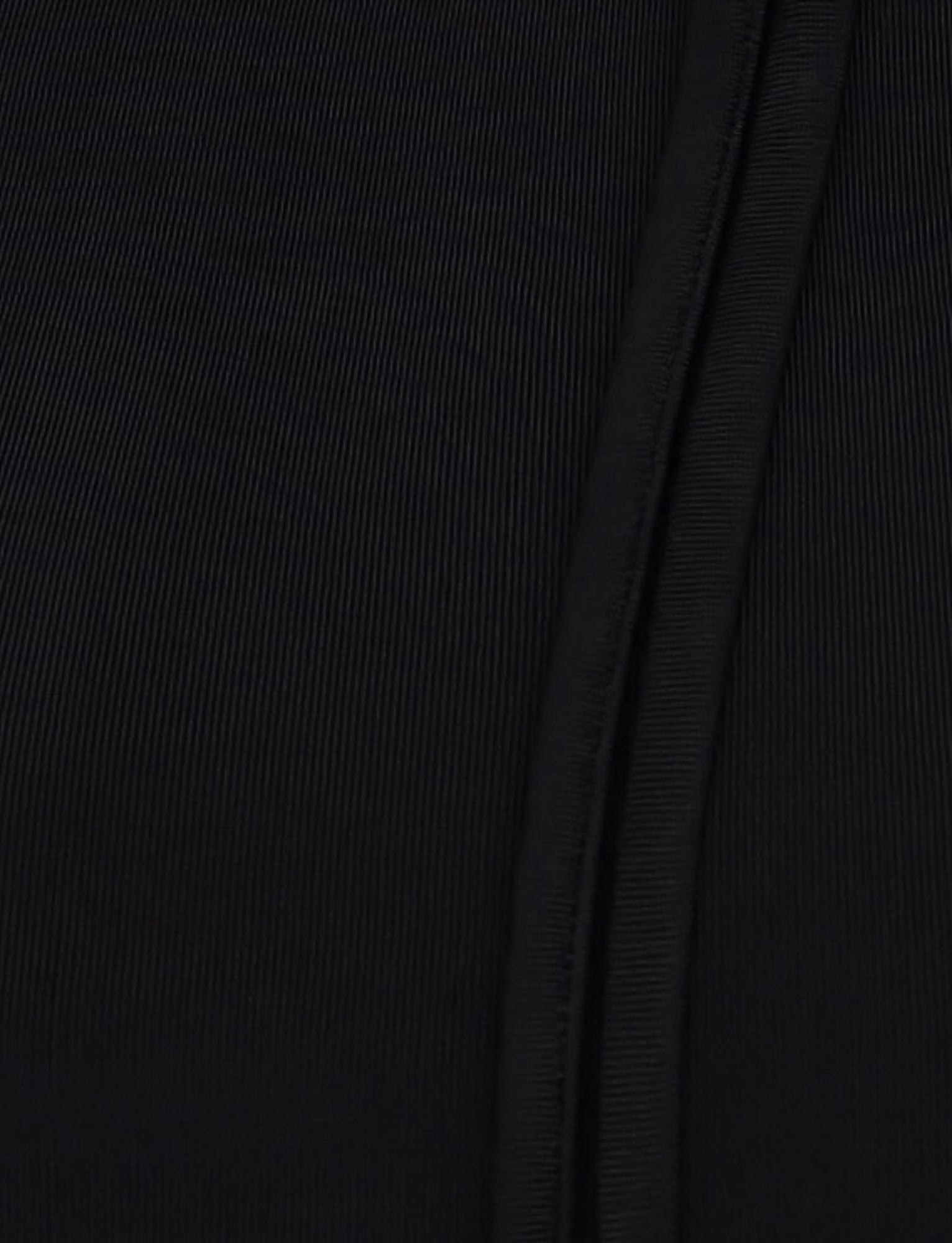 Close-up image of the MIETTA TOP - BLACK from TIGERMIST, featuring fabric with fine vertical ridges and a seam running vertically on the right side. The high-stretch, ribbed fabric is slightly stretchy, ideal for its multi-tie neck design.