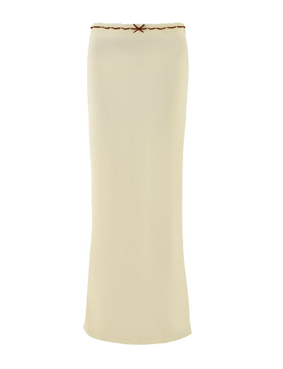 Introducing the FENNEL SKIRT by TIGERMIST in a pale yellow hue. This long, tube-style skirt boasts a simple yet elegant design, featuring a decorative bow at the top edge and delicate lace trim for added charm. Its smooth texture and straight silhouette complete the minimalistic look.