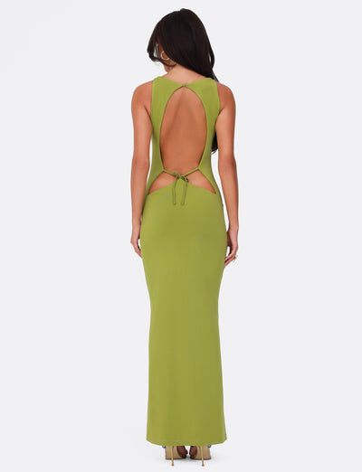 A woman in the SONNET MAXI DRESS - GREEN by TIGERMIST stands facing away. She has long hair and is wearing high heels. The dress features a sweetheart neckline, tie detail, halter neck, and maxi-length skirt against a plain white background.