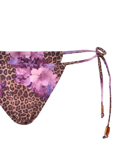 The TIGERMIST DESIRAE Bikini Bottom in Purple features a bold floral leopard print, adjustable side ties with purple straps, and wooden bead details.