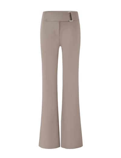 The VESPER PANT - BROWN : TAN by TIGERMIST are high-waisted, flare-leg pants in a solid tan color, featuring a front zipper and a metal buckle detail on the waistband. The smooth, slightly stretchy fabric provides a tailored fit with a full-length silhouette.