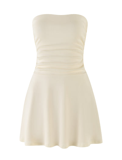 The HARRIETT RIB MINI DRESS in cream from TIGERMIST features a fitted bodice and a flared skirt. The smooth fabric is slightly gathered at the waist in this strapless design, set against a plain white background.