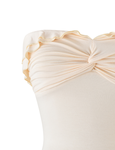 Close-up of the DENALI BOOB TUBE - NEUTRAL : BONE by TIGERMIST, an off-white strapless bandeau with a center twist detail and ruffled neckline, crafted from stretchy fabric.