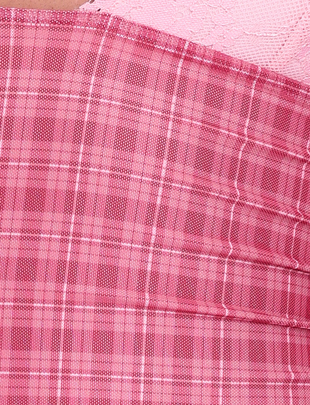Close-up of the NAVIA DRESS - RED by TIGERMIST, featuring red check plaid fabric with pleats and a contrasting section with a subtle lace-like floral texture, both shown at an angle.