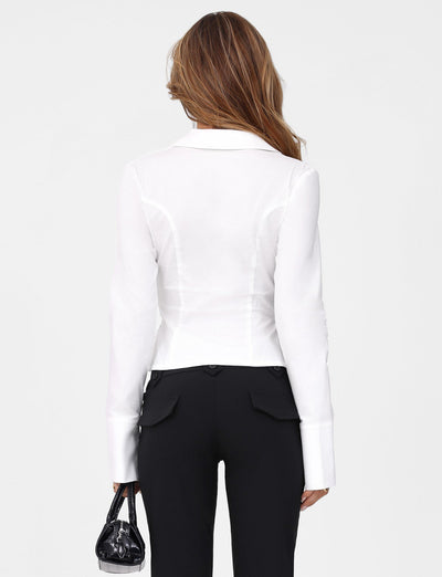 A person with long hair wears a TIGERMIST BRIELLE SHIRT in white ivory and black pants, holding a small black handbag. The crisp white background highlights the sleek look, reminiscent of soft stretch fabric offering both comfort and style.