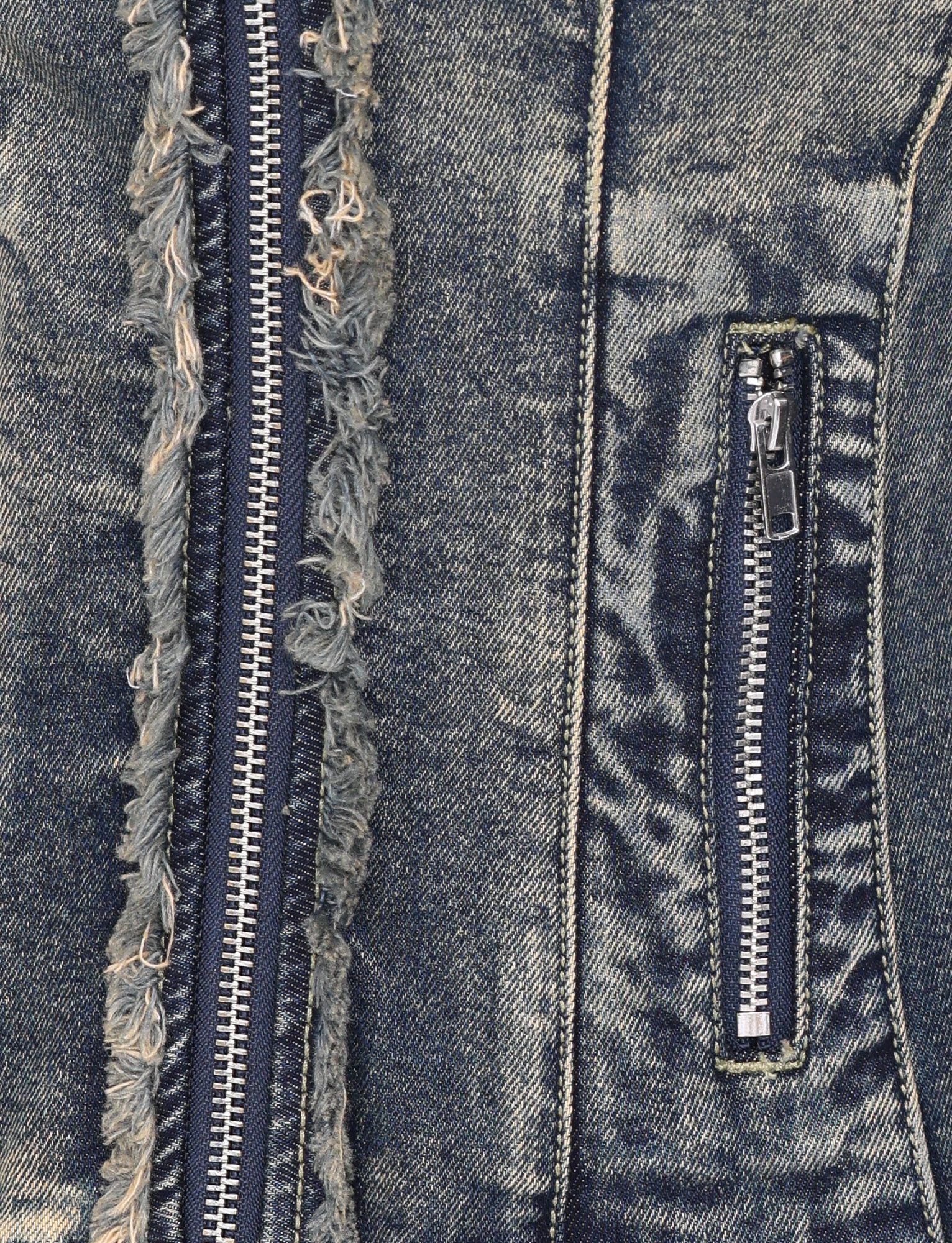 Close-up of the OPHELIE JACKET - BLUE by TIGERMIST, featuring vintage wash denim with two zippers—one vertical with frayed edges and one smaller on the pocket—showcasing its textured, worn details.