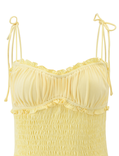 The SAFIRA TOP - LEMON by TIGERMIST is a light yellow jersey camisole with a bodycon fit, ruched fabric, ruffled bust details, and thin shoulder straps tied into bows.