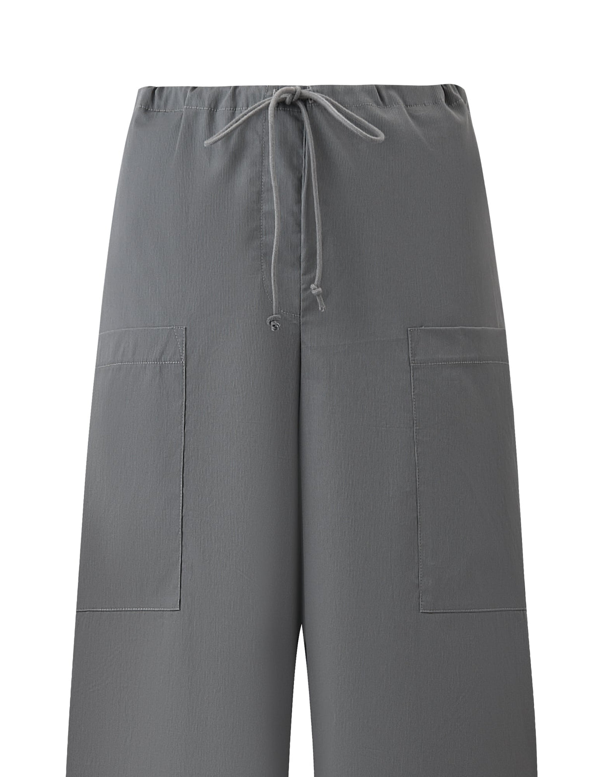The TYSHA PANT - CHARCOAL by TIGERMIST features a relaxed wide-leg fit, two large square front pockets, an elastic waistband with center drawstring tie, and a slightly crinkled texture. Background is plain white.