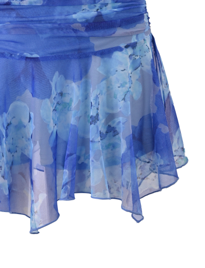 A close-up of the DEVYN MINI SKORT - BLUE MACRO FLORAL by TIGERMIST, featuring sheer, flowy fabric, an asymmetrical hemline, and a mid rise fit with light blue and white floral patterns for a fresh look.
