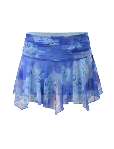 The DEVYN MINI SKORT by TIGERMIST features a flowy, sheer blue macro floral print, an asymmetrical handkerchief hemline, layered details, and a ruched waistband for a dreamy mid rise mini look.