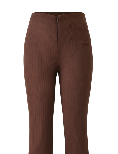 The GWENDOLINE PANT - CHOCOLATE by TIGERMIST features brown high-waisted, flared ribbed legs, a front zipper, and a single side patch pocket—offering a modern twist on classic suit pants, shown against a plain white background.