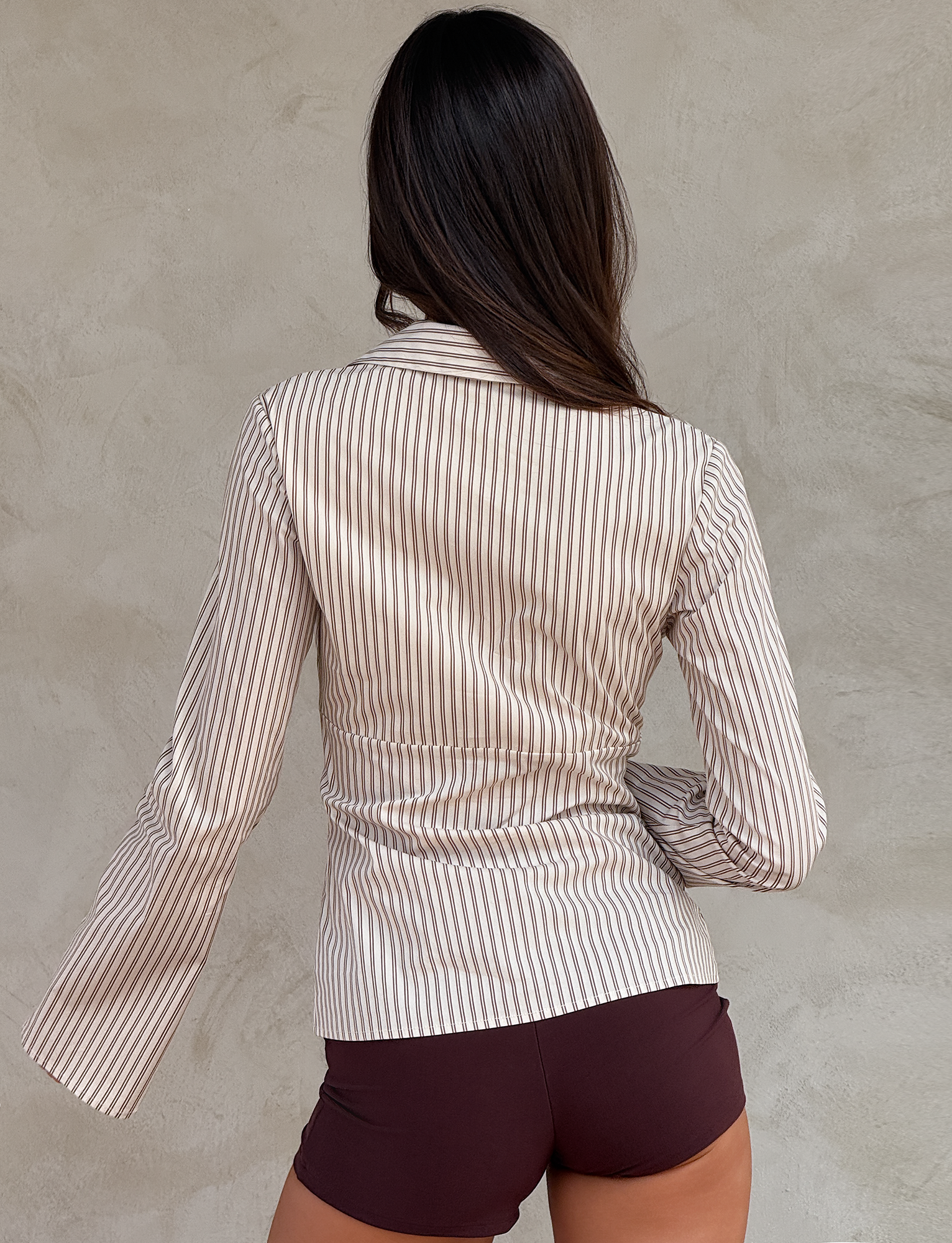 A woman wearing the SABRINE SHIRT - BEIGE STRIPE by TIGERMIST.