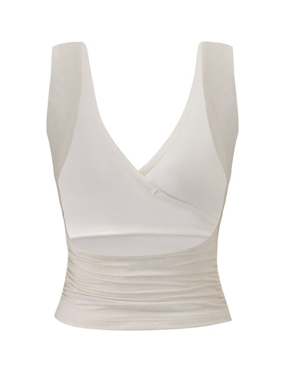 The NURA TOP - IVORY by TIGERMIST is a sleeveless off-white wrap top featuring wide straps, a deep V-neckline, and ruched waist detailing, shown against a plain white background.