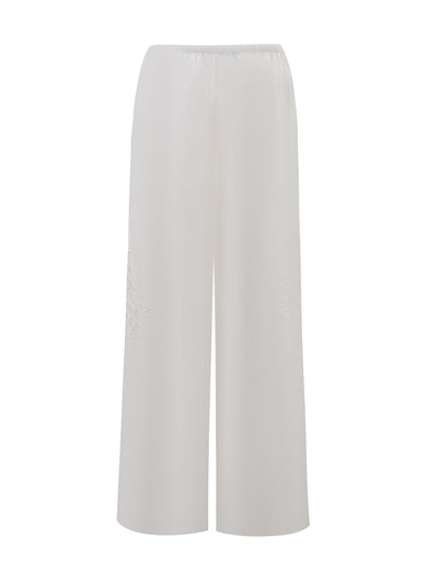 The TIGERMIST CRESSY PANT - WHITE is a full-length, wide-leg cotton pant featuring a high waist, elastic waistband, and subtle leg embroidery, shown against a plain white background.