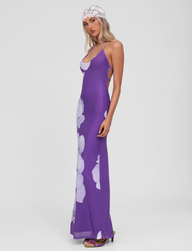 A woman stands sideways against a white background, wearing the TIGERMIST NOUR MESH MAXI DRESS in Purple Macro Floral and a white lace headscarf, looking at the camera with a neutral expression.