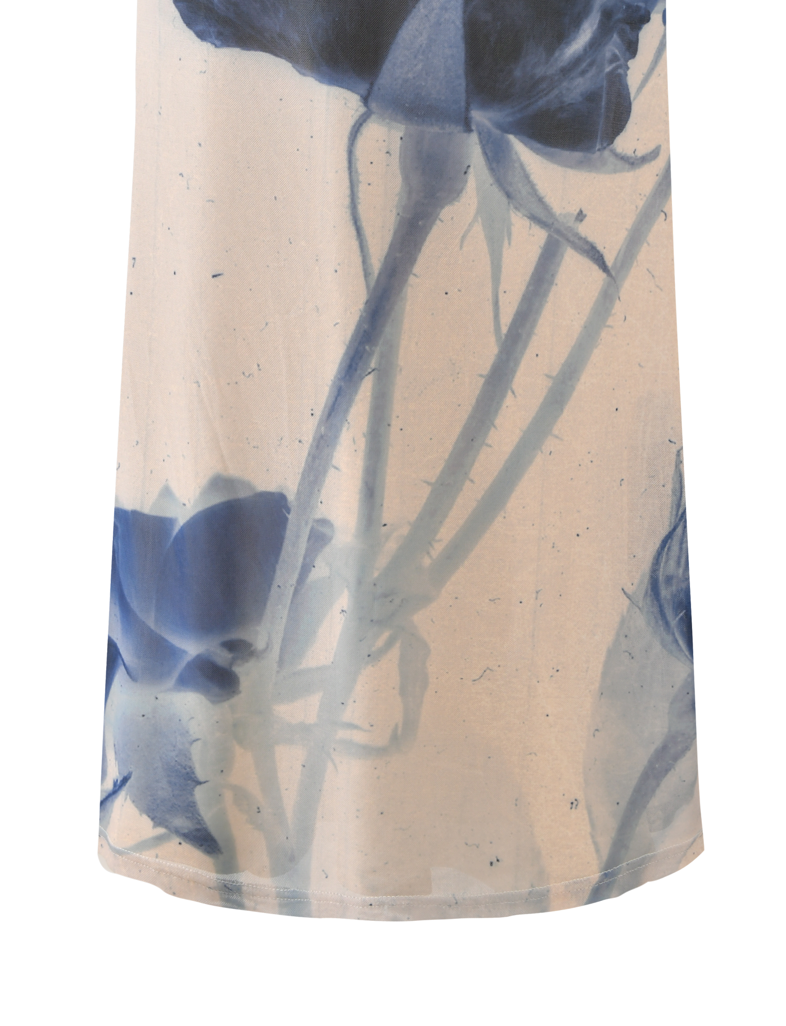 A close-up of the TIGERMIST JANIS MAXI SKIRT - INDIGO FLORAL shows semi-transparent fabric with large blue floral designs and stems on a light beige background.