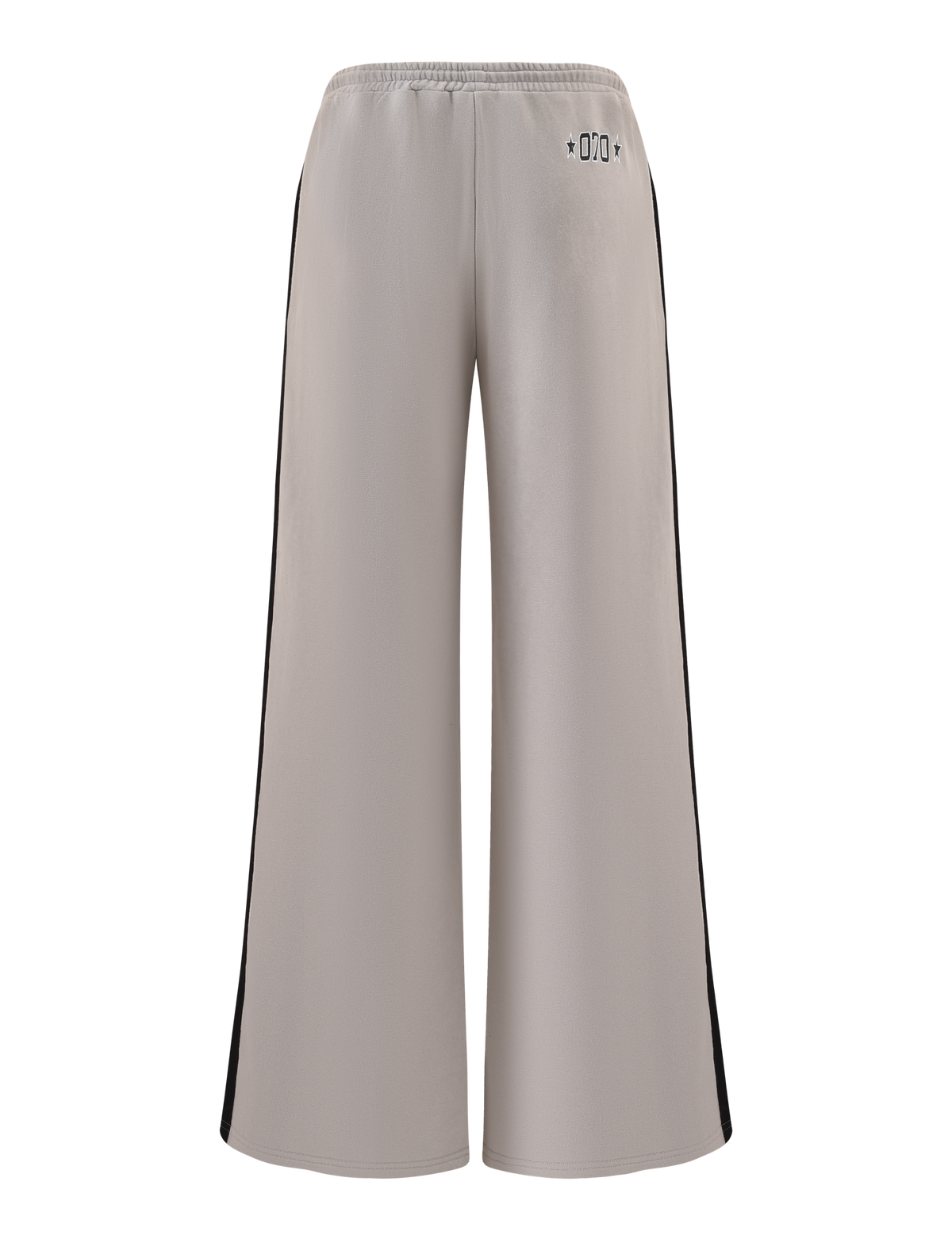 The PAYTON TRACKPANT - STONE by TIGERMIST features a wide-leg fit, taupe cotton fabric, elastic waistband, black side panels, and small black symbols near the back waist. The sporty pants are shown against a white background.