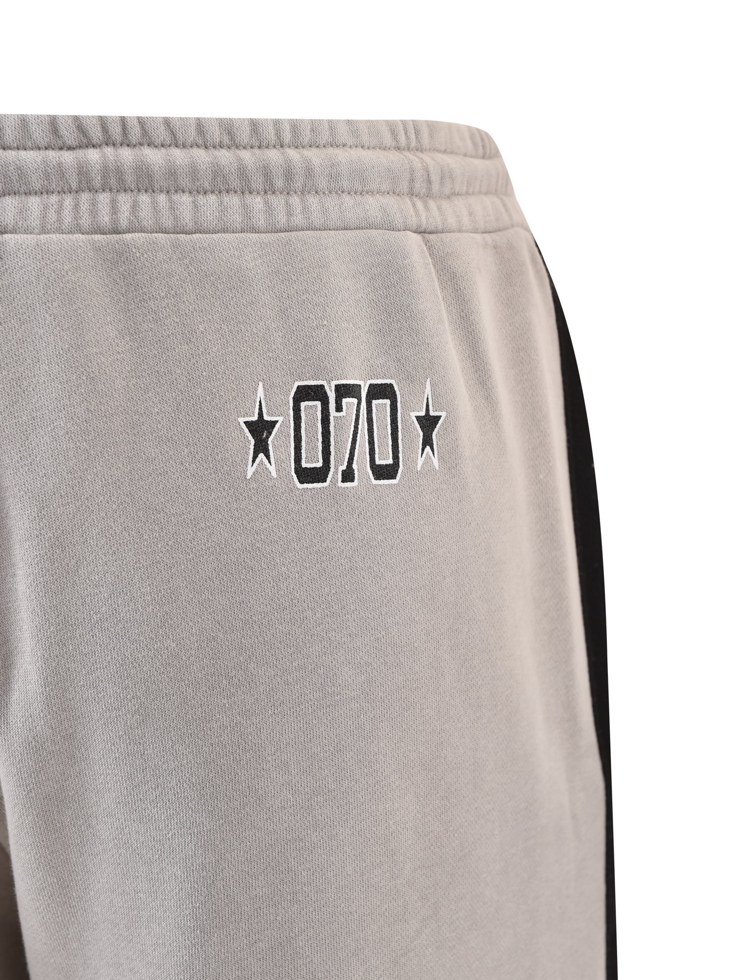 Close-up of TIGERMIST PAYTON TRACKPANT - STONE: grey cotton trackpants with "070" and stars embroidered in black on the left hip, plus a black vertical stripe down the side for a sporty look.