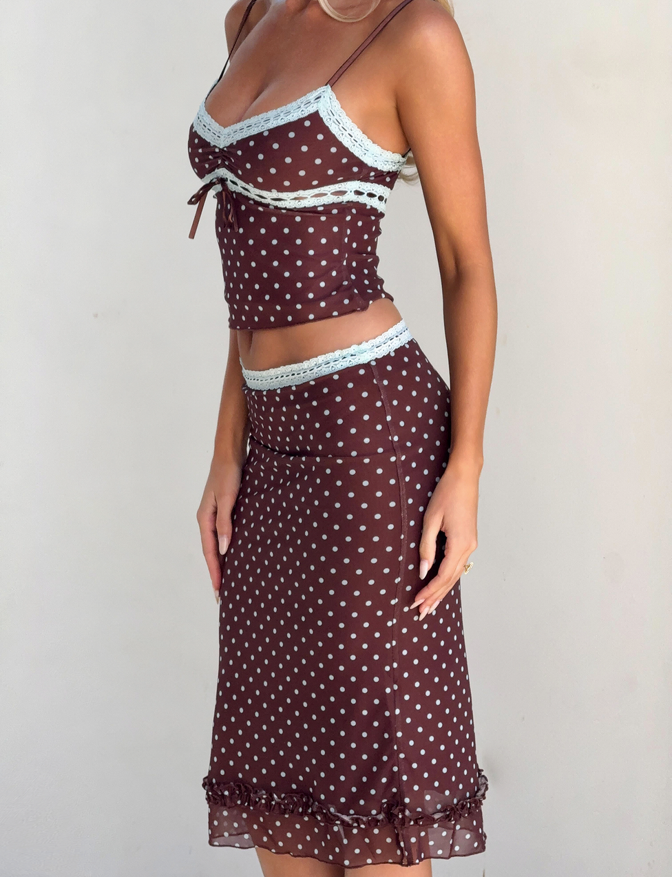 A woman models the TIGERMIST AMARA MIDI SKIRT - POLKA DOT, paired with a matching sleeveless camisole, against a plain light background.