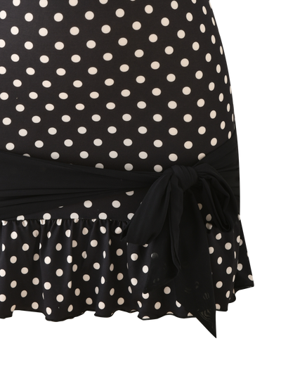 The TIGERMIST TOVE MINI DRESS - BLACK POLKA DOT is a strapless mini dress with a ruffle hem and a black fabric sash tied at the waist.