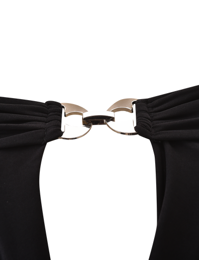 Close-up of a metallic clasp joining the straps of the TIGERMIST JENESIS LONG SLEEVE TOP in black, set against a plain white background.